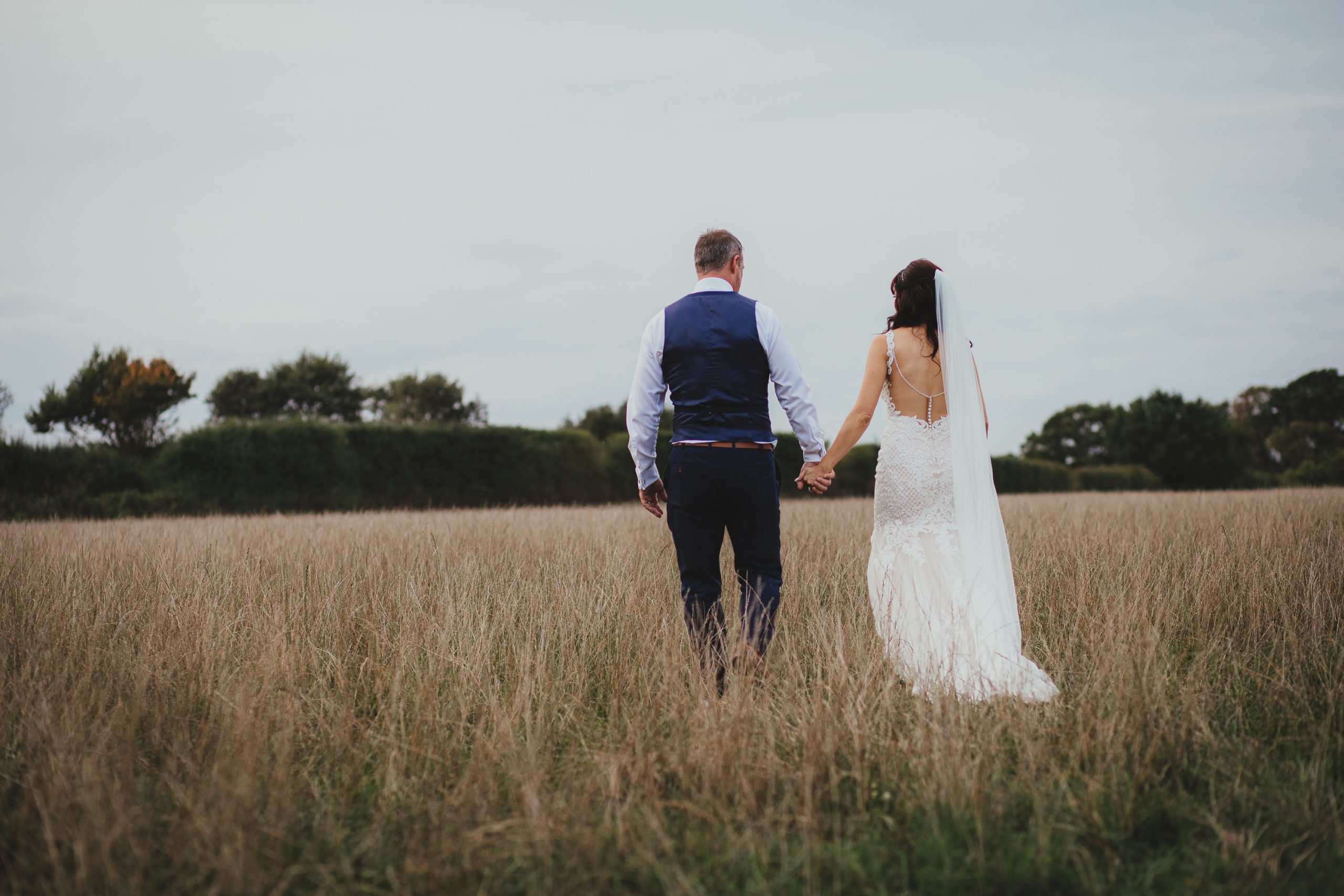 boho bride and groom in field at festival wedding
