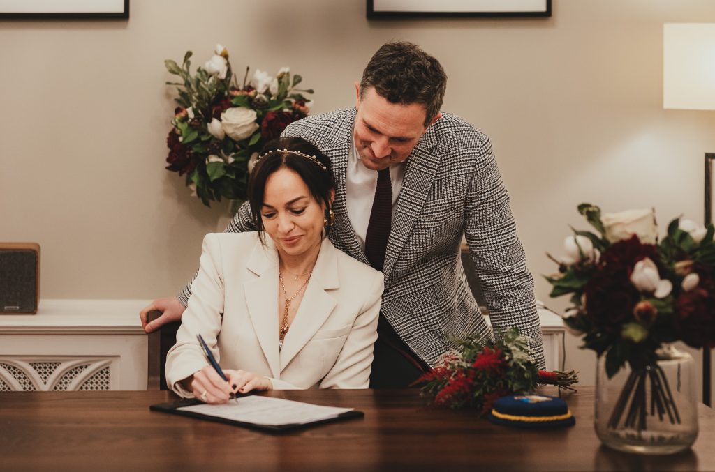 Couple signing the register during their Chelsea Old Town Hall ceremony, London.