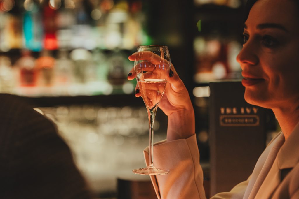 Couple holding a champagne glass at the bar after their wedding