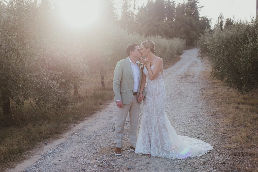 Relaxed married couple at their wedding in Italy, kissing in the olive groves at golden hour