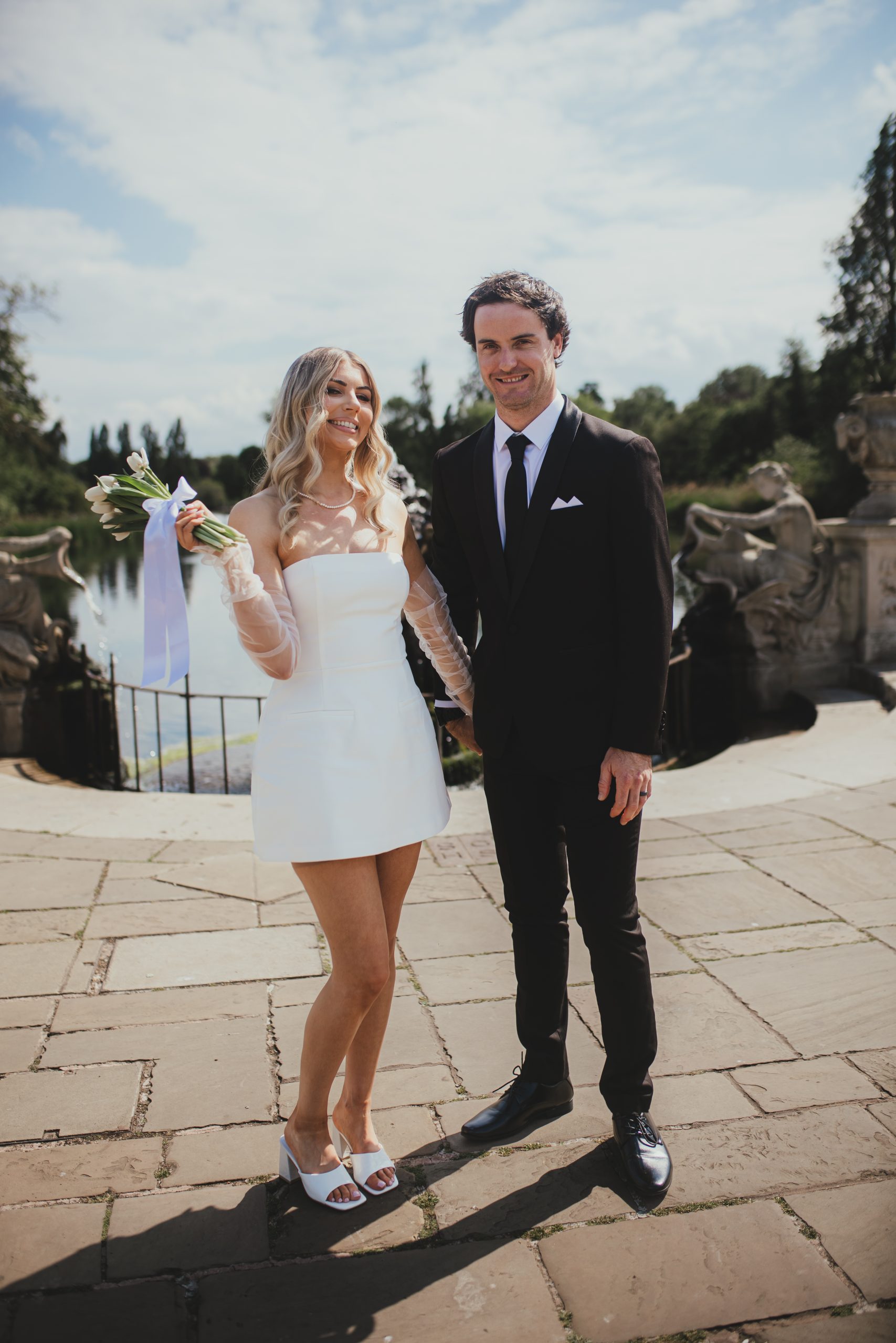 Bride in a short wedding dress holding flowers during London portraits
