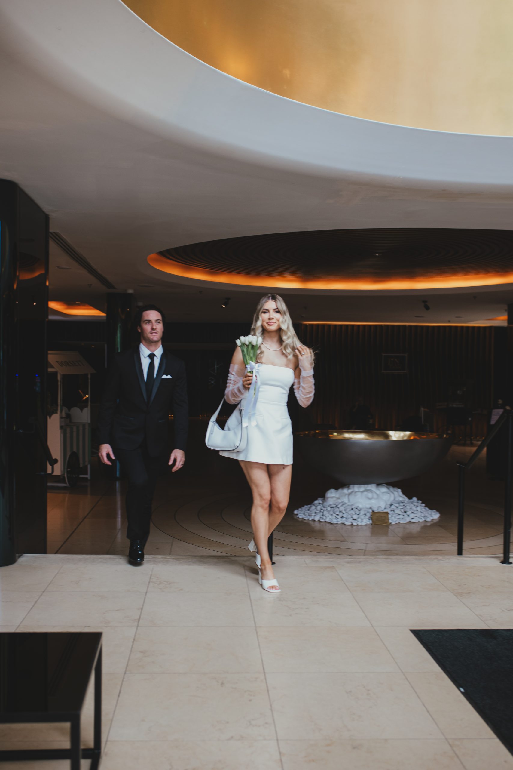 Bride walking through a London hotel lobby in a short wedding dress