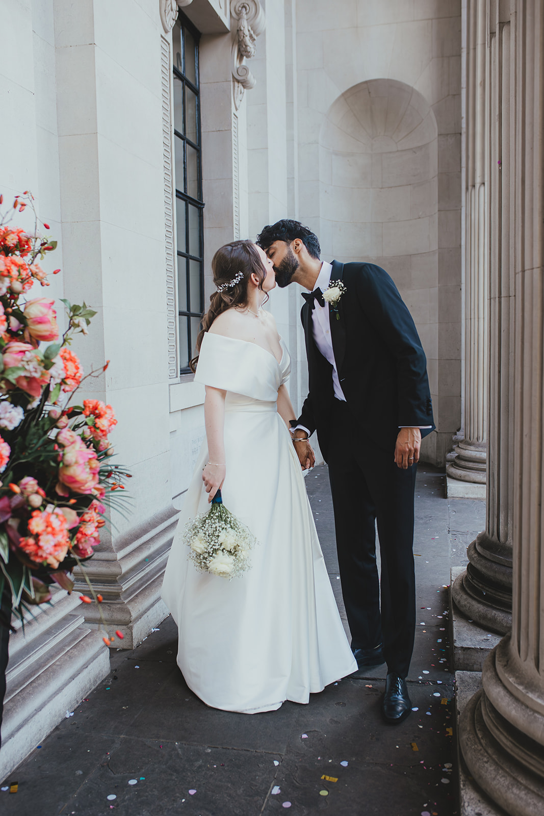 Bride and groom share a kiss beside the columns at Old Marylebone Town Hall, London