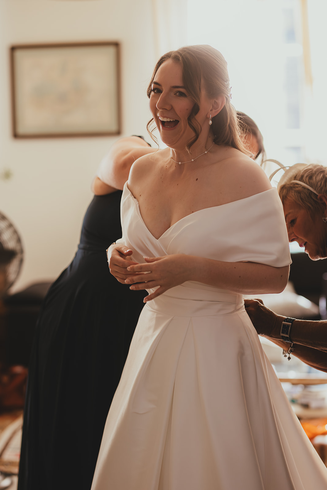 Bride smiling in her wedding dress during final touches before leaving.