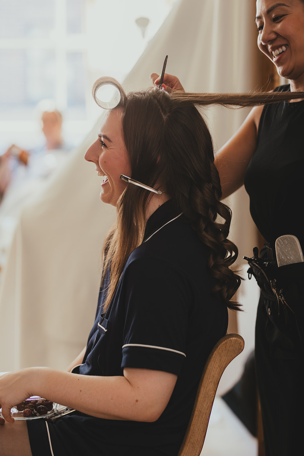 Bride smiling as her hair is curled during morning prep.