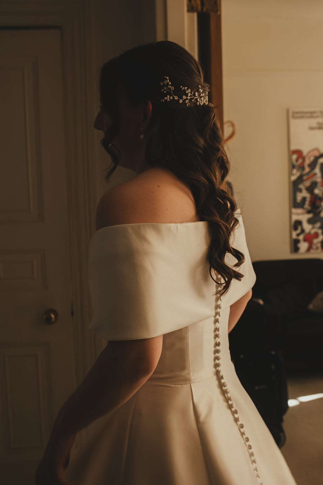 Bride in her dress seen from behind as she moves through the house.