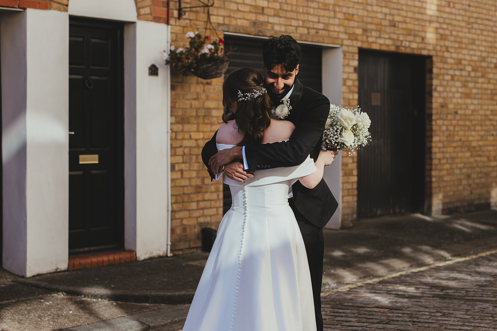 Couple hugging tightly on a London street during their first look, Old Marylebone Town Hall, London