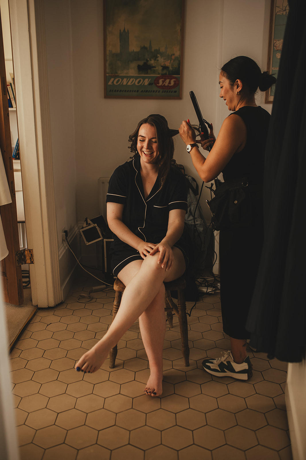 Bride laughing while having her hair styled in the kitchen before the wedding