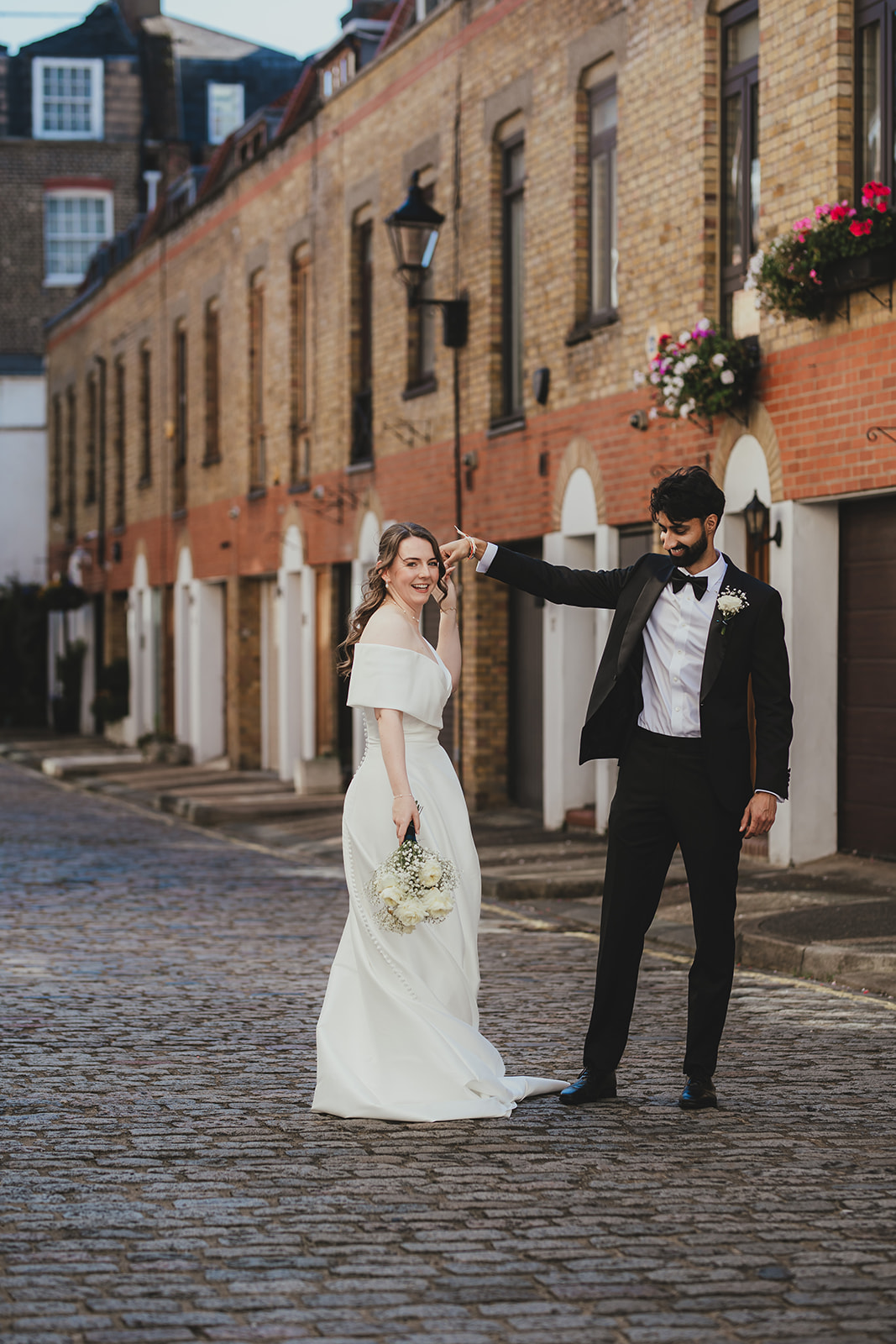 Bride smiling at the groom during their first look on a cobbled London mews