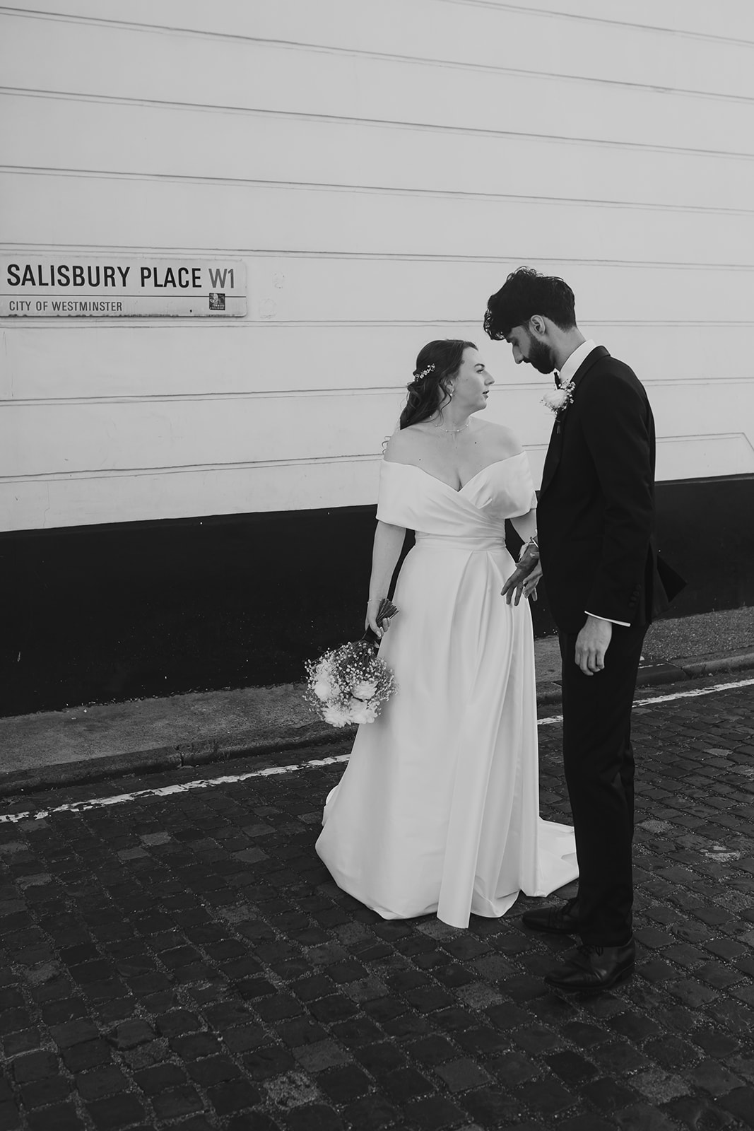 Bride and groom pose beneath the Salisbury Place W1 street sign in London