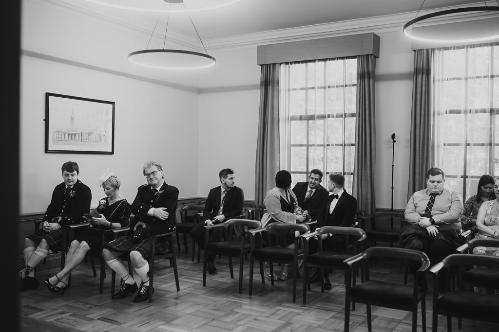Black and white wide shot of guests seated in the Old Marylebone Town Hall ceremony room
