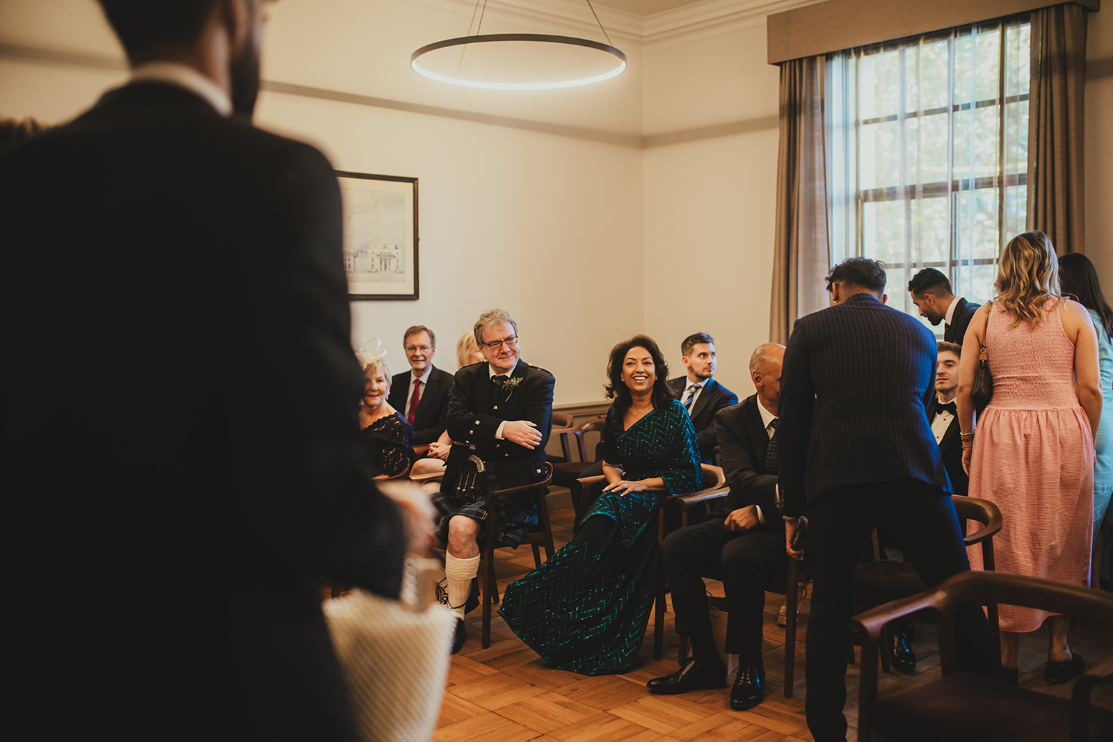 Guests chat and smile in the Old Marylebone Town Hall ceremony room before the ceremony