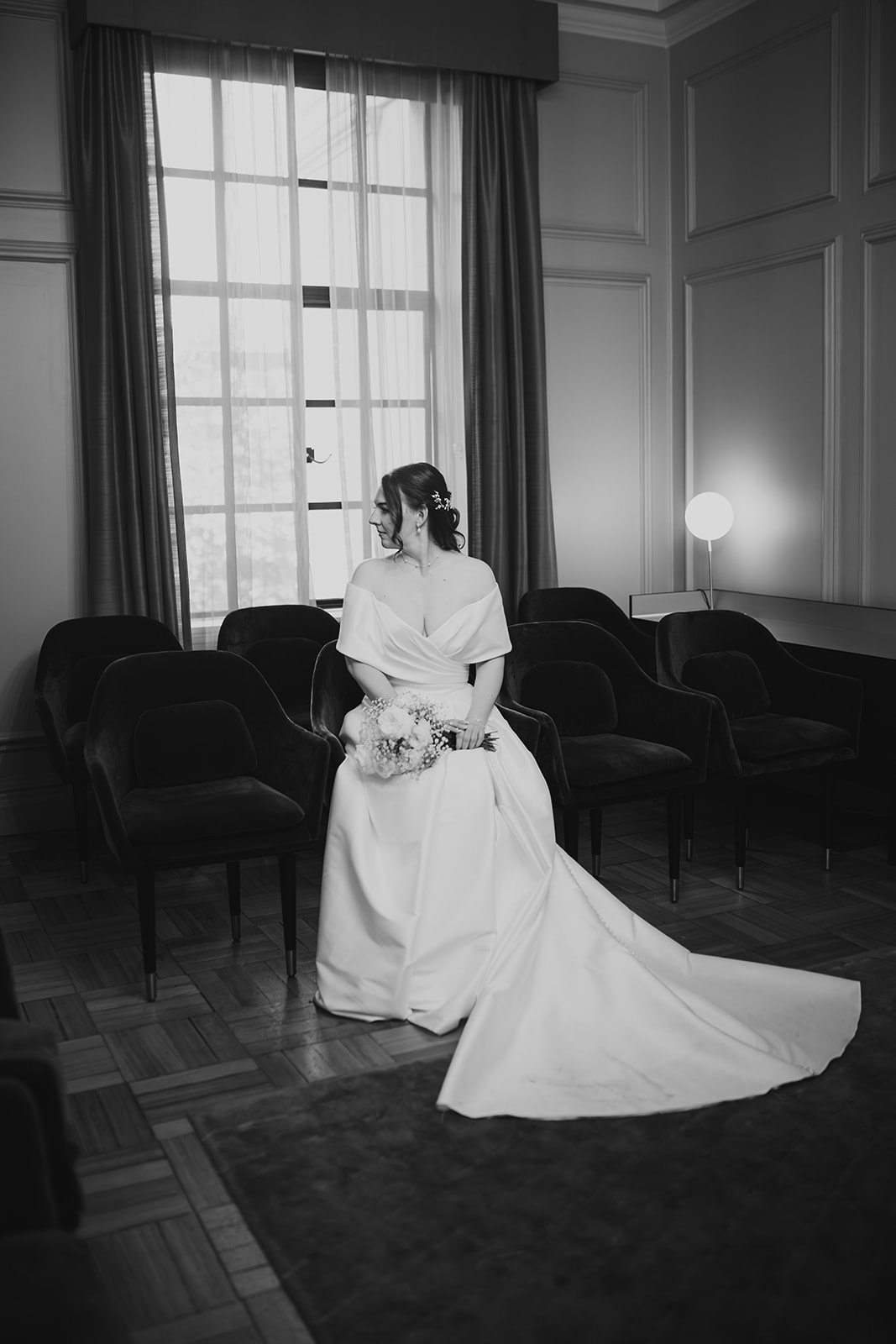 Bride sits holding her bouquet in the Mayfair Room at Old Marylebone Town Hall