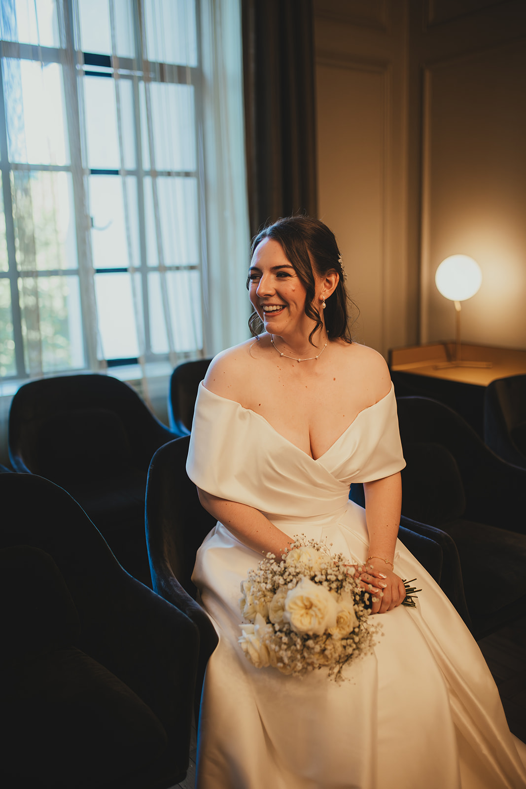 Bride sits holding her bouquet in the Mayfair Room at Old Marylebone Town Hall