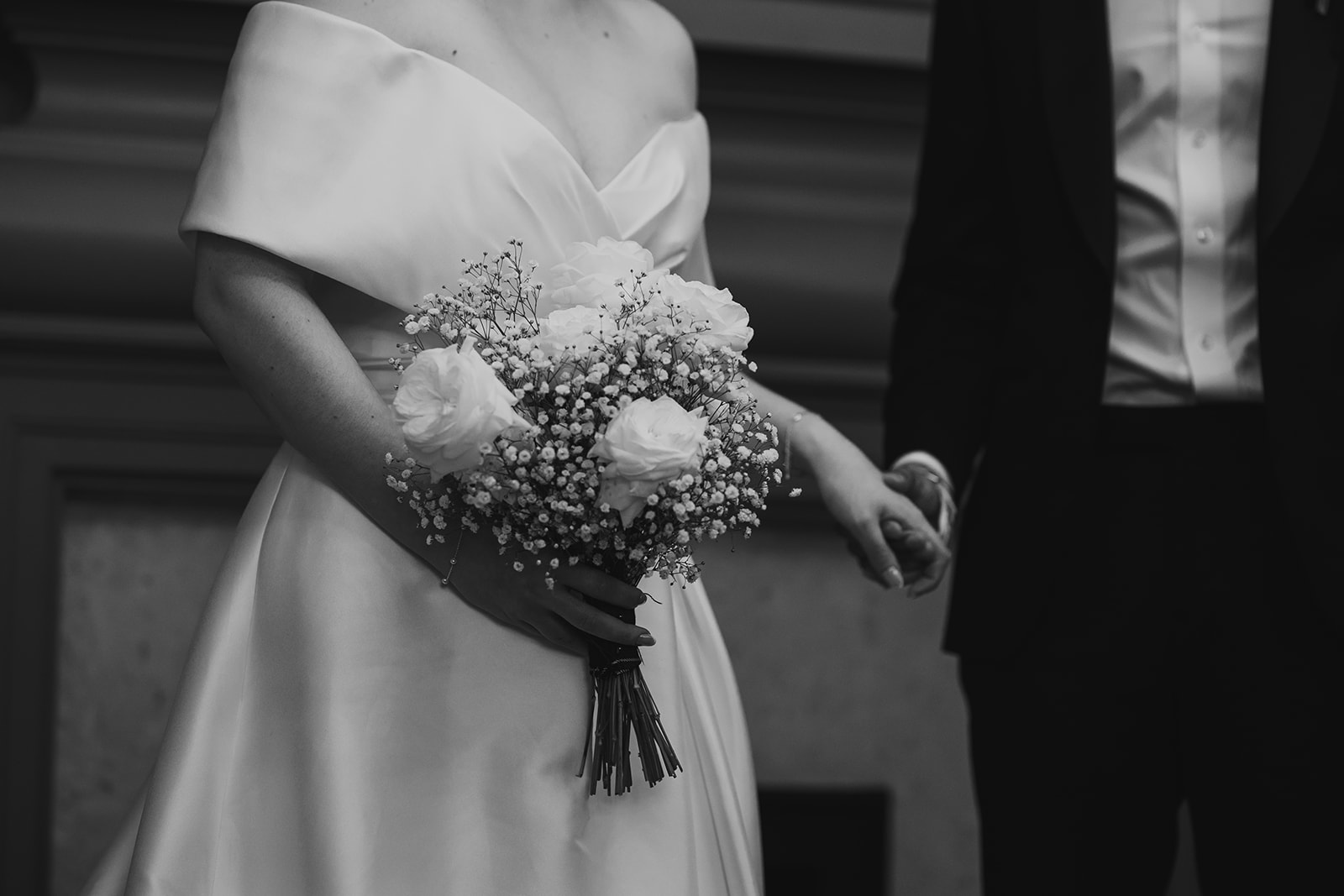 Black and white close-up of the bride’s bouquet held at her waist