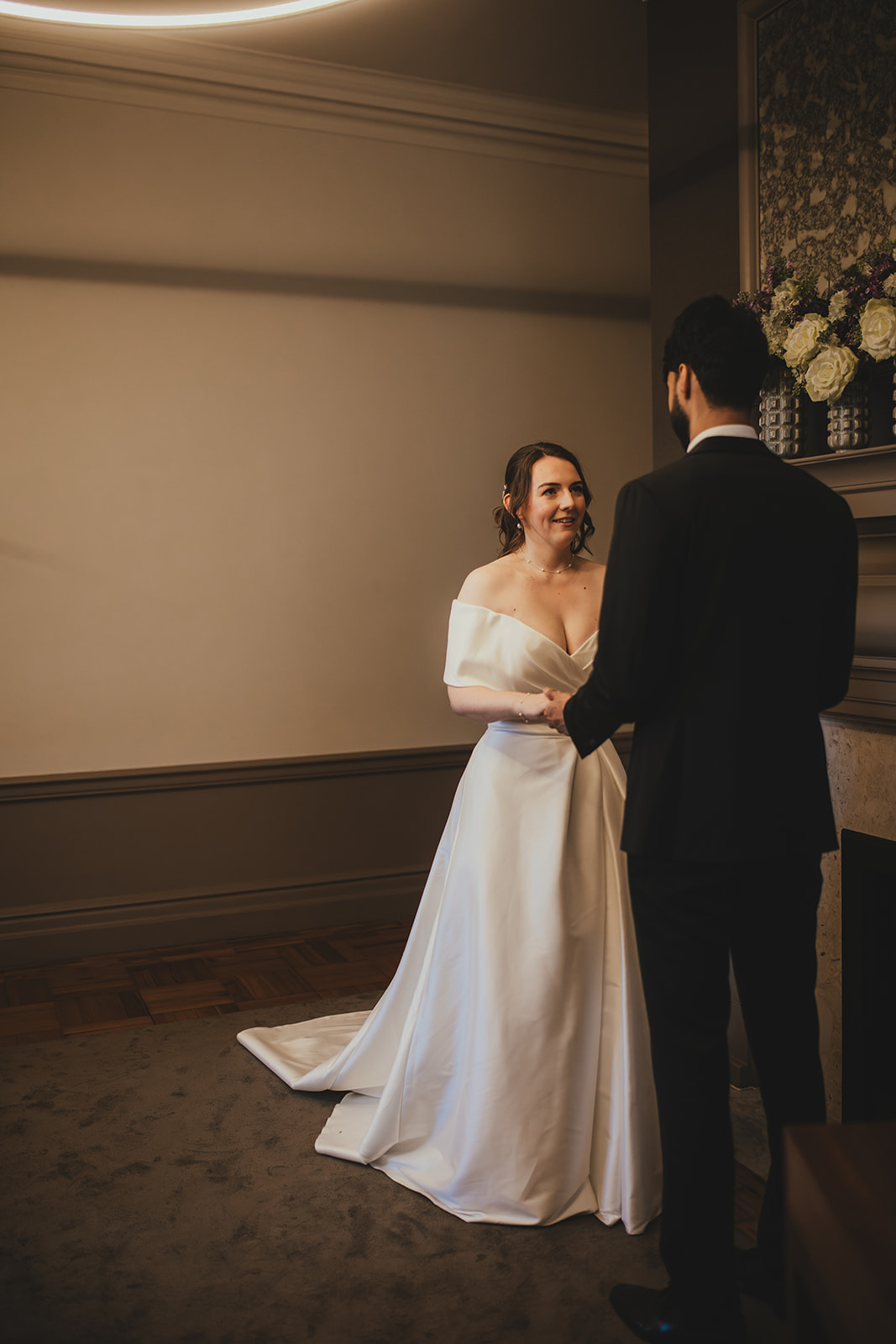 Bride and groom hold hands during their ceremony in the Mayfair Room at Old Marylebone Town Hall