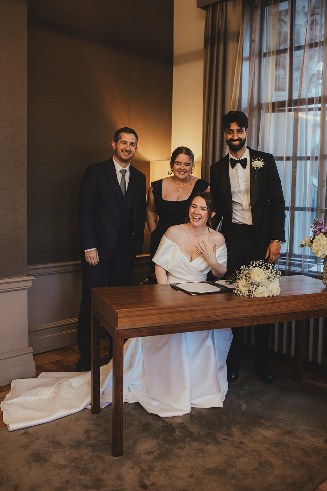 Bride laughs at the signing table with the groom and witnesses at Old Marylebone Town Hall