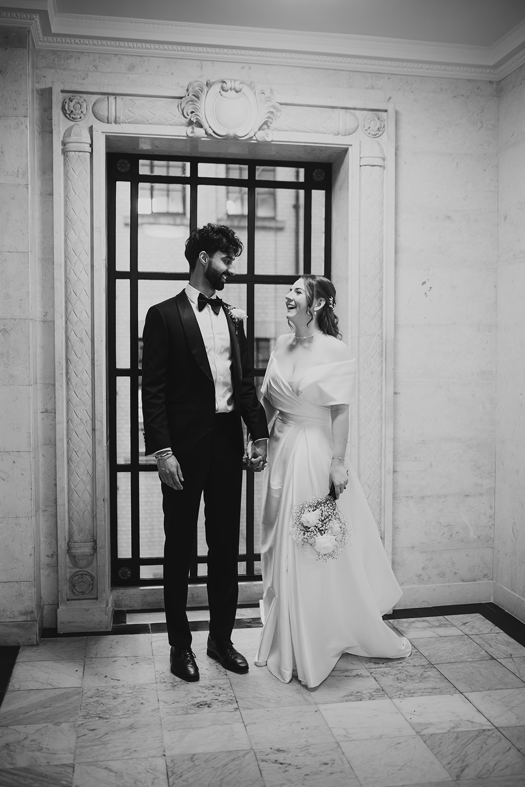 Black and white photo of the bride and groom laughing together inside Old Marylebone Town Hall