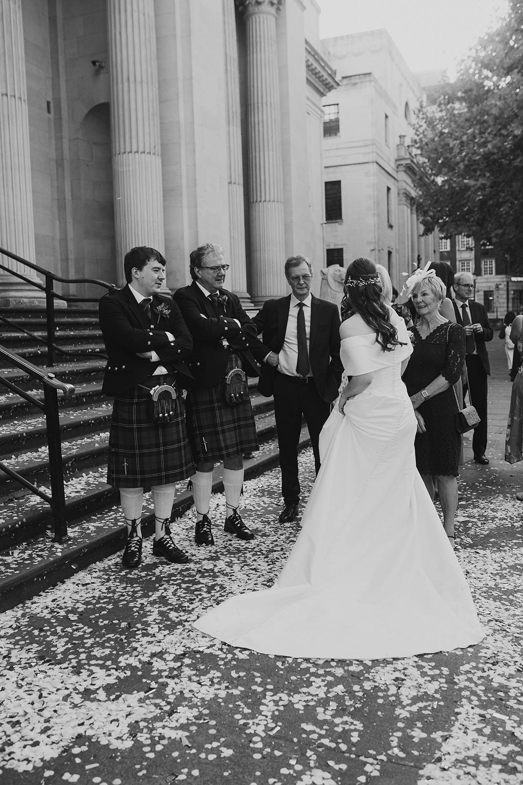 Bride chats with guests on the confetti-covered steps at Old Marylebone Town Hall (black and white)