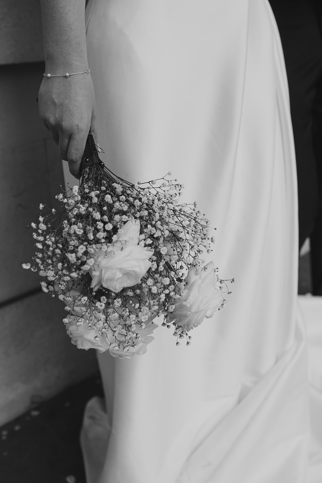 Black and white close-up of the bride’s bouquet held at her side