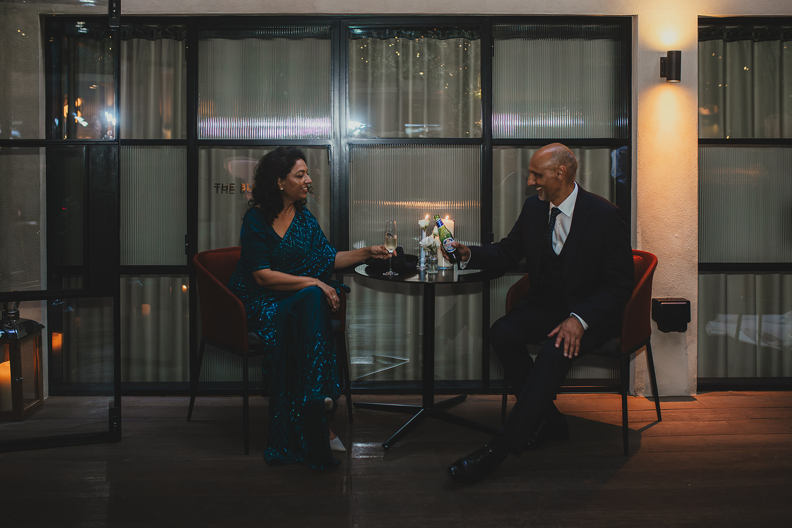 Two guests clinking champagne glasses at a table in the evening