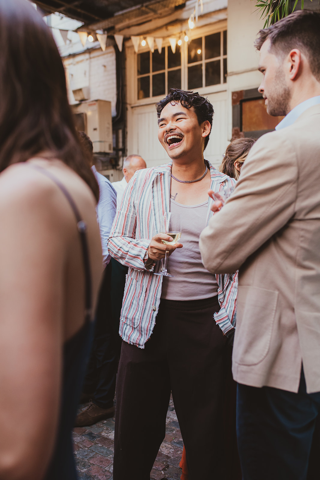 Guests laughing in court yard at The Depot N7 wedding reception, London wedding