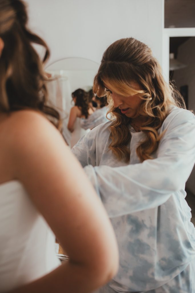 Bride helping bridesmaid getting into wedding dress, Islington Town Hall wedding, London wedding