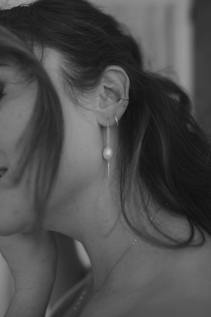 Bride putting on pearl earrings, London wedding