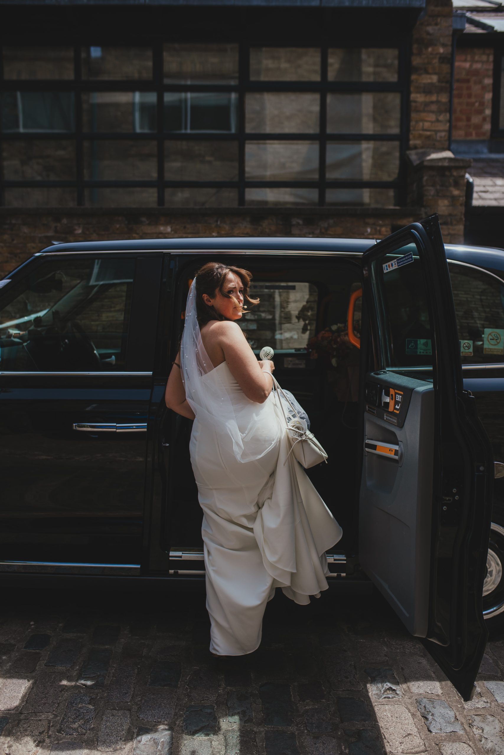 Bride getting into taxi to leave fro ceremony at Islington Town Hall