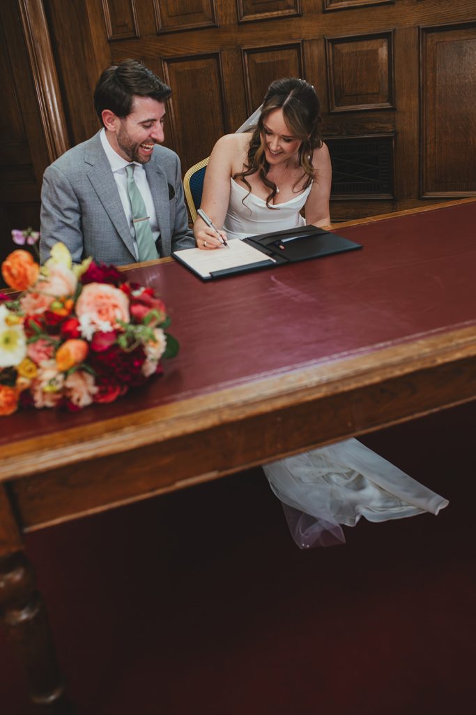 Bride and groom signing the registry at Islington Town Hall, London wedding