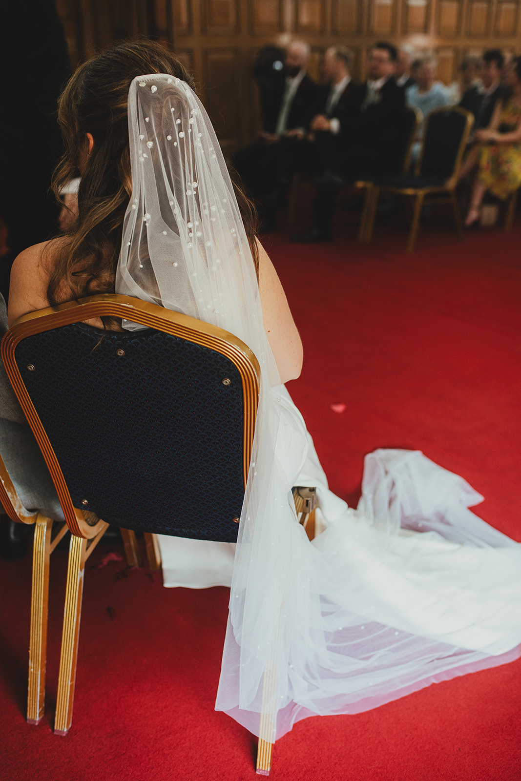 Detail of bride's viel and dress from behind while sitting during ceremony at Islington Town Hall, London wedding