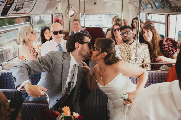 Bride and groom kiss on route master bus outside Islington Town Hall on their way to the wedding reception at The Depot N7