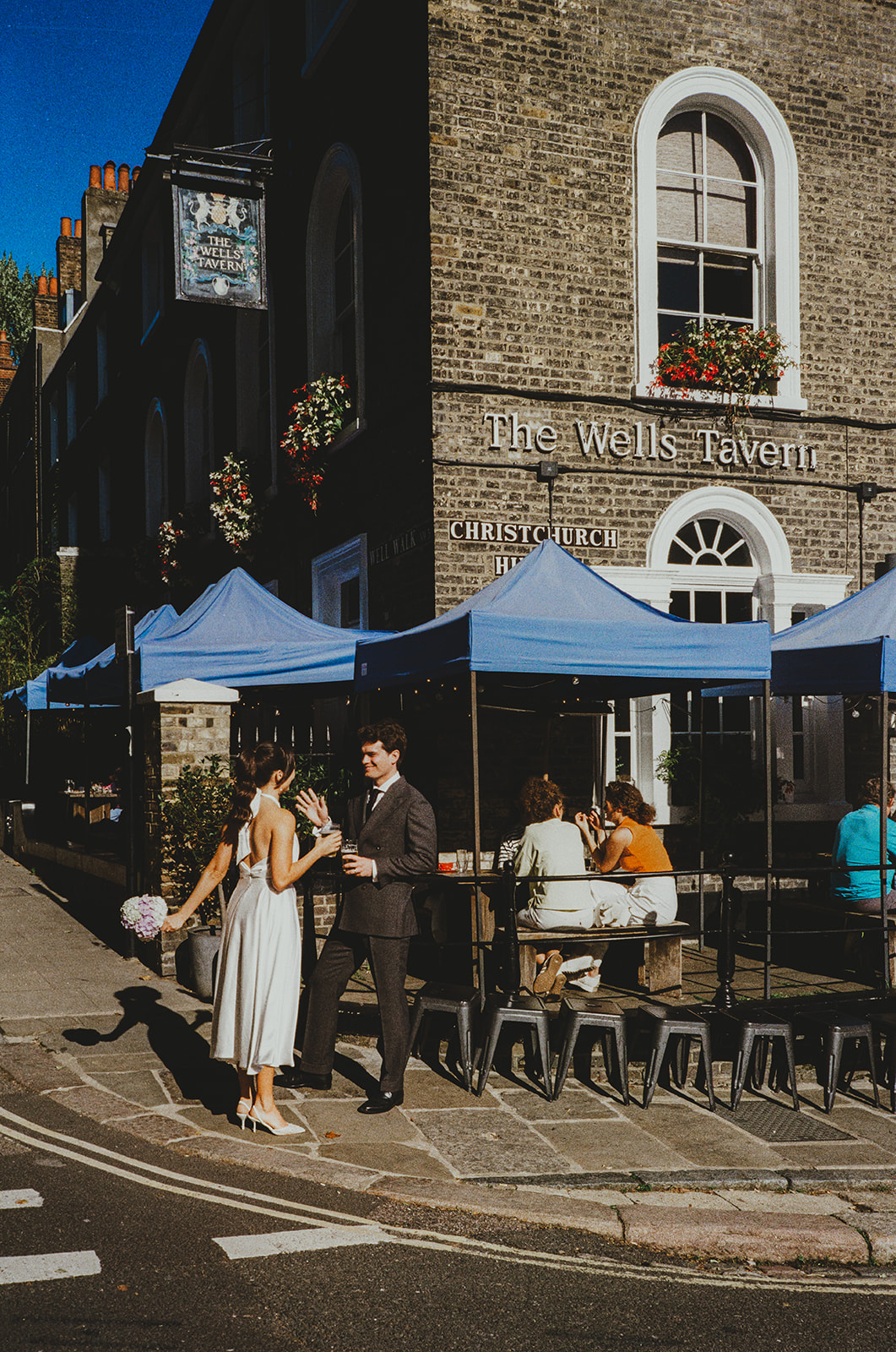 Bride and groom drinking outside pub in Hampstead 