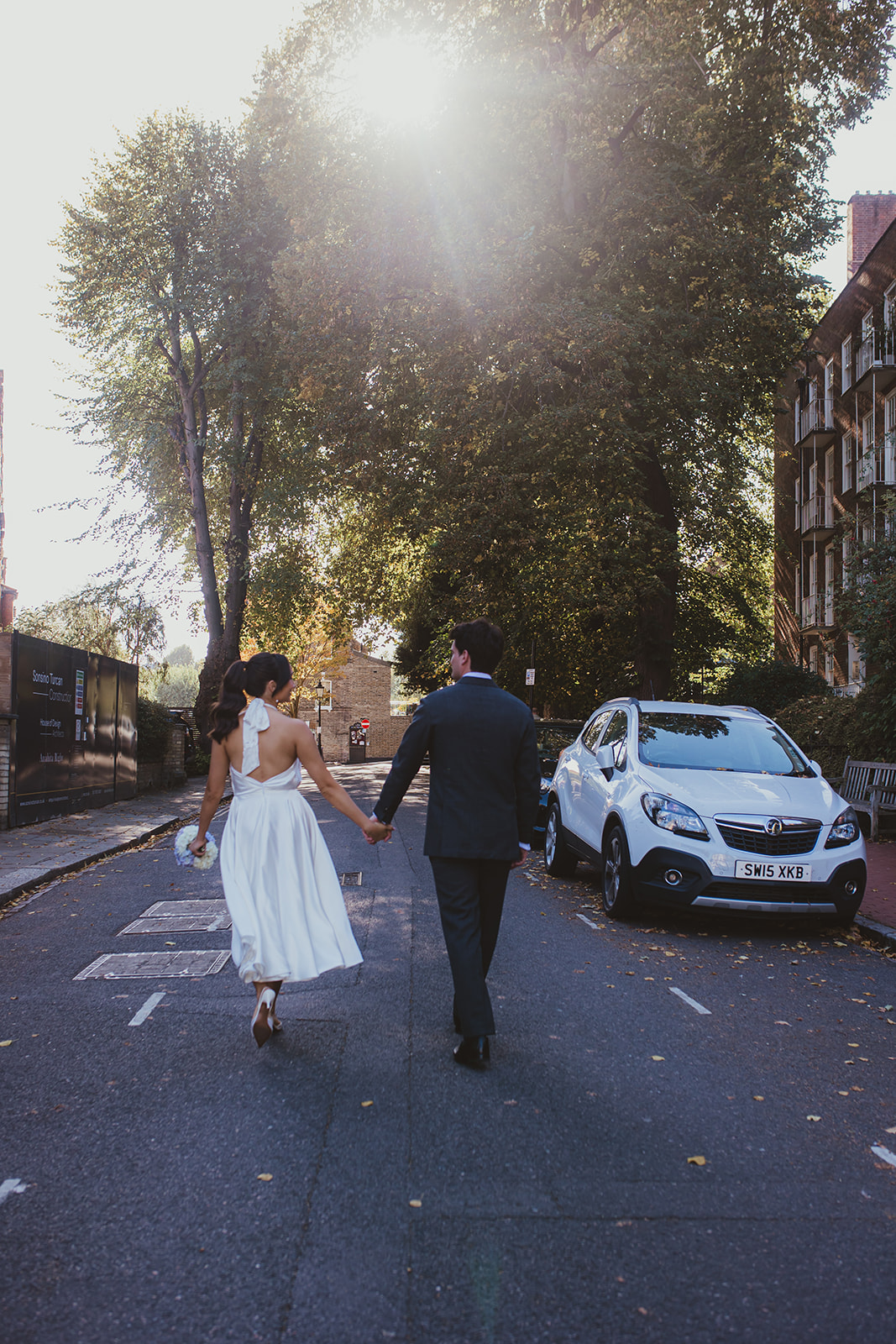 Bride and groom holding hands and walking down the road