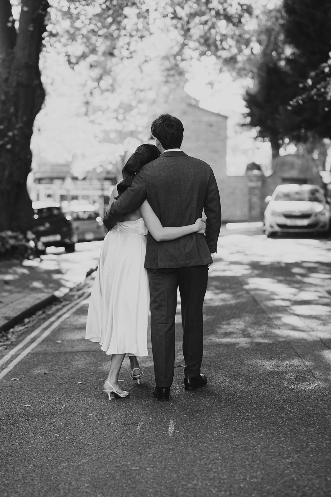 Bride and groom with arms around each other while they walk away down the street