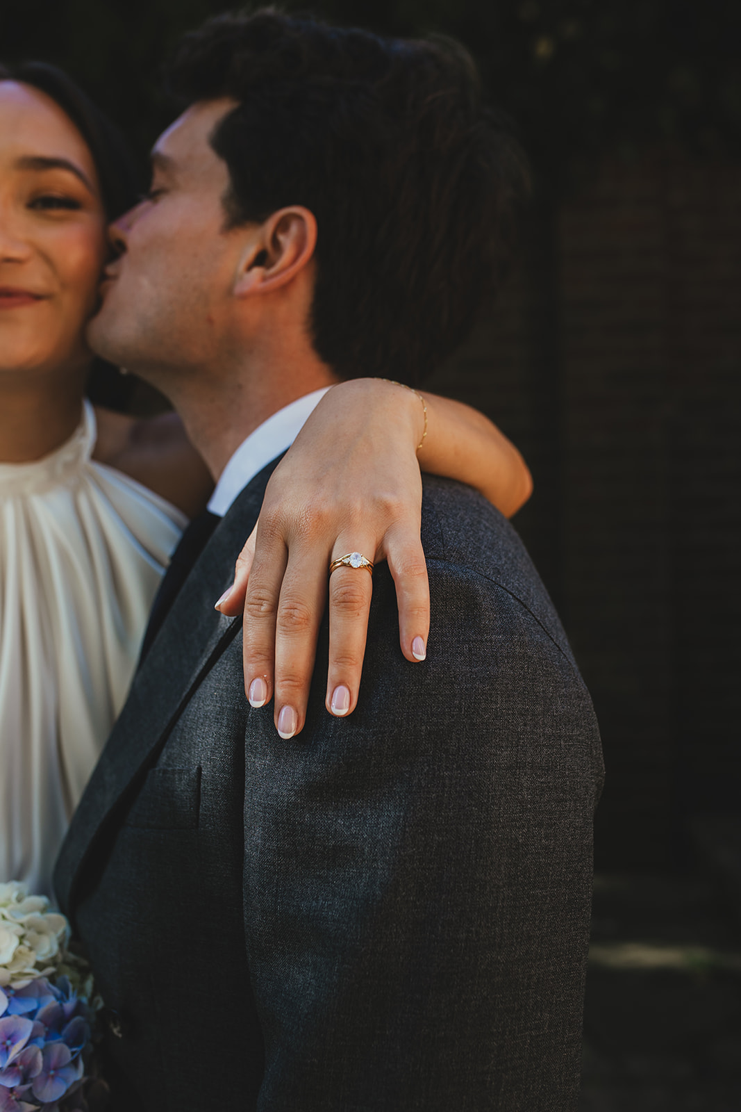 detail photo of bride's ring while her arm is around the groom's shoulders