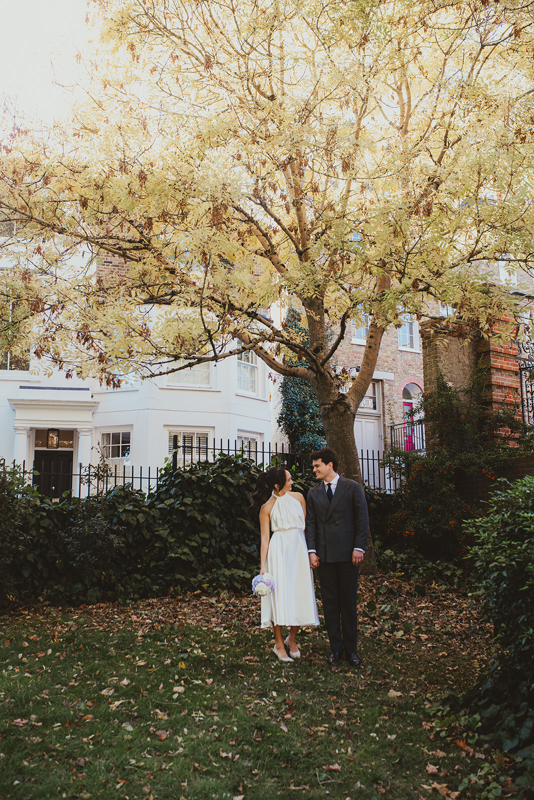 Bride and groom under a golden leaved tree in autumn in Hampstead Heath