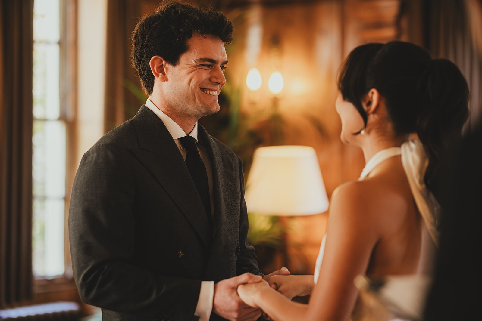Groom holding hands and looking at bride during wedding ceremony