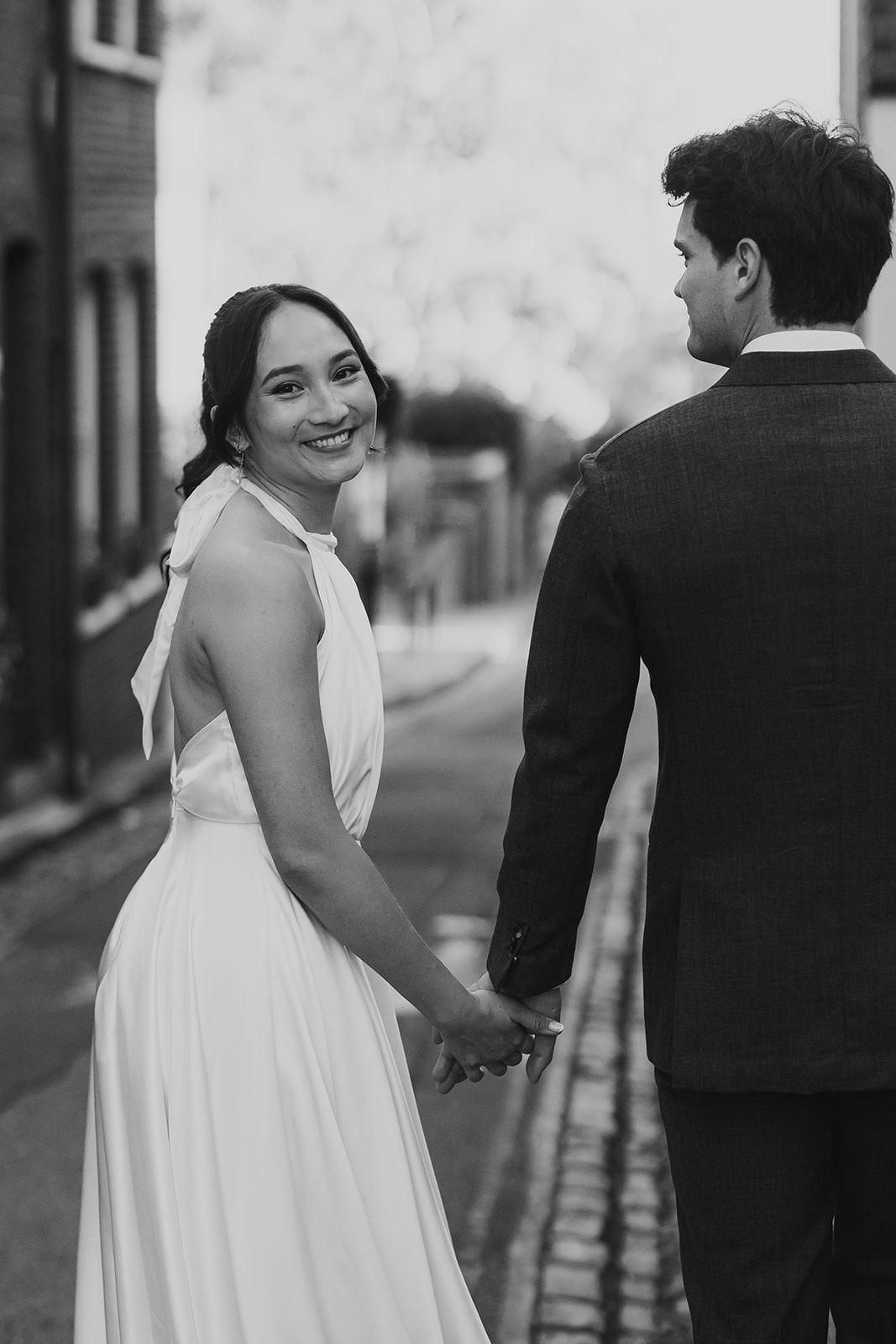 Bride turning round while holding groom's hand and walking away
