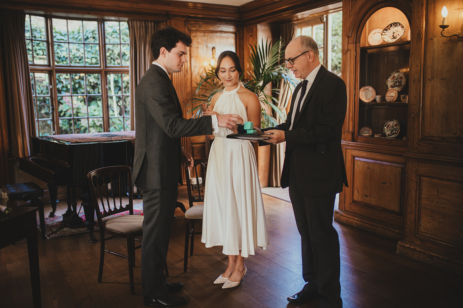 The bride taking the ring to place on the groom's finger during their wedding ceremony at Burgh House