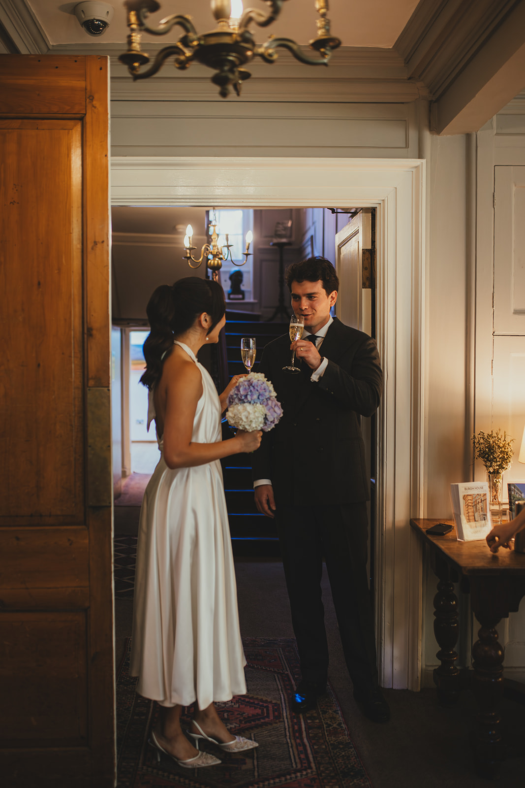 Bride and groom with champagne in the hallway after getting married