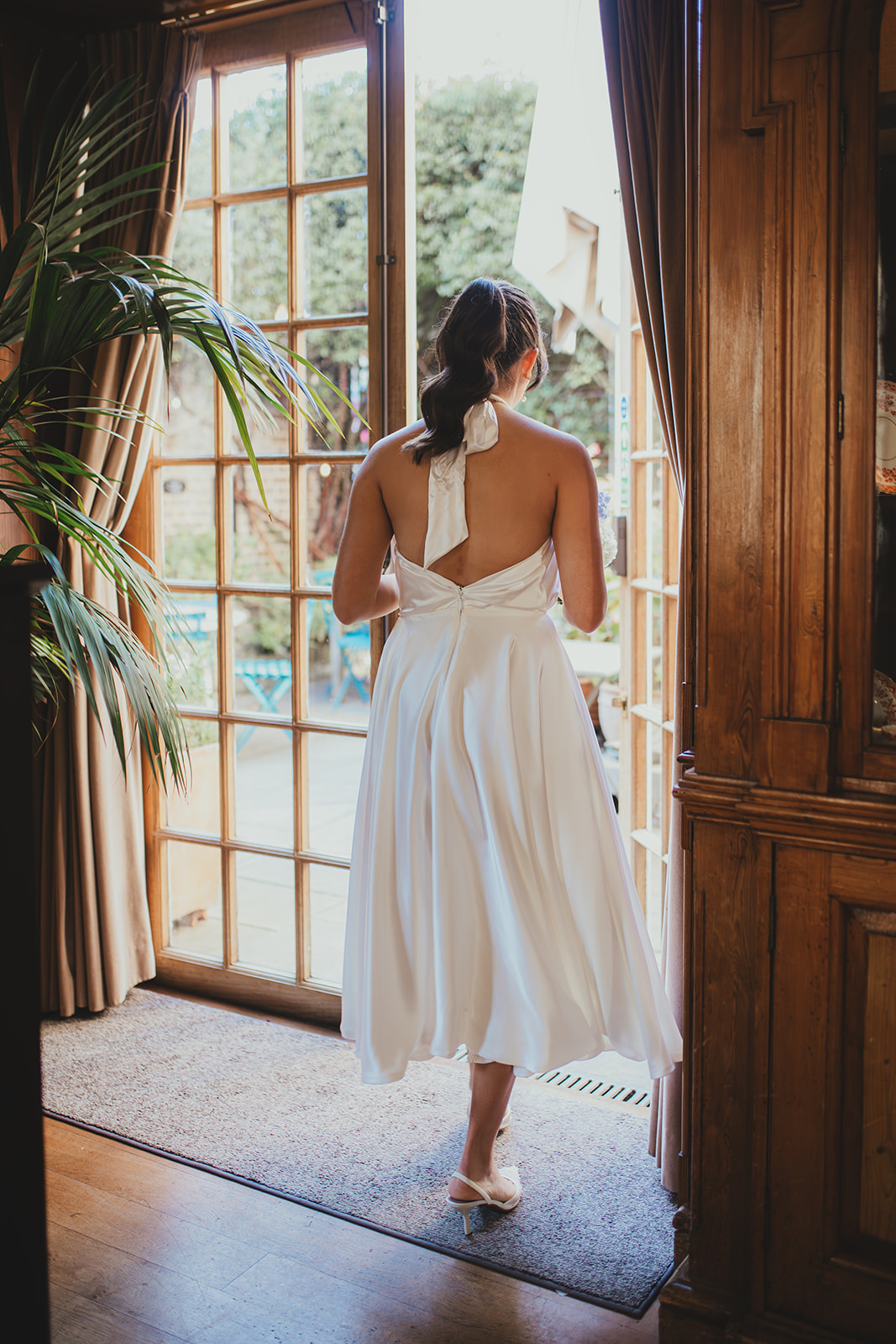The back of the bride as she walks to the courtyard at Burgh House 
