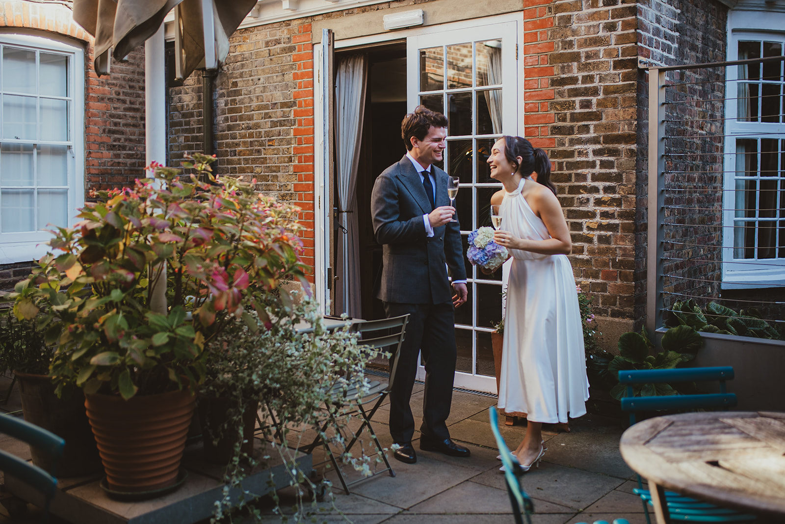 Bride and groom laughing together in the courtyard of burgh House