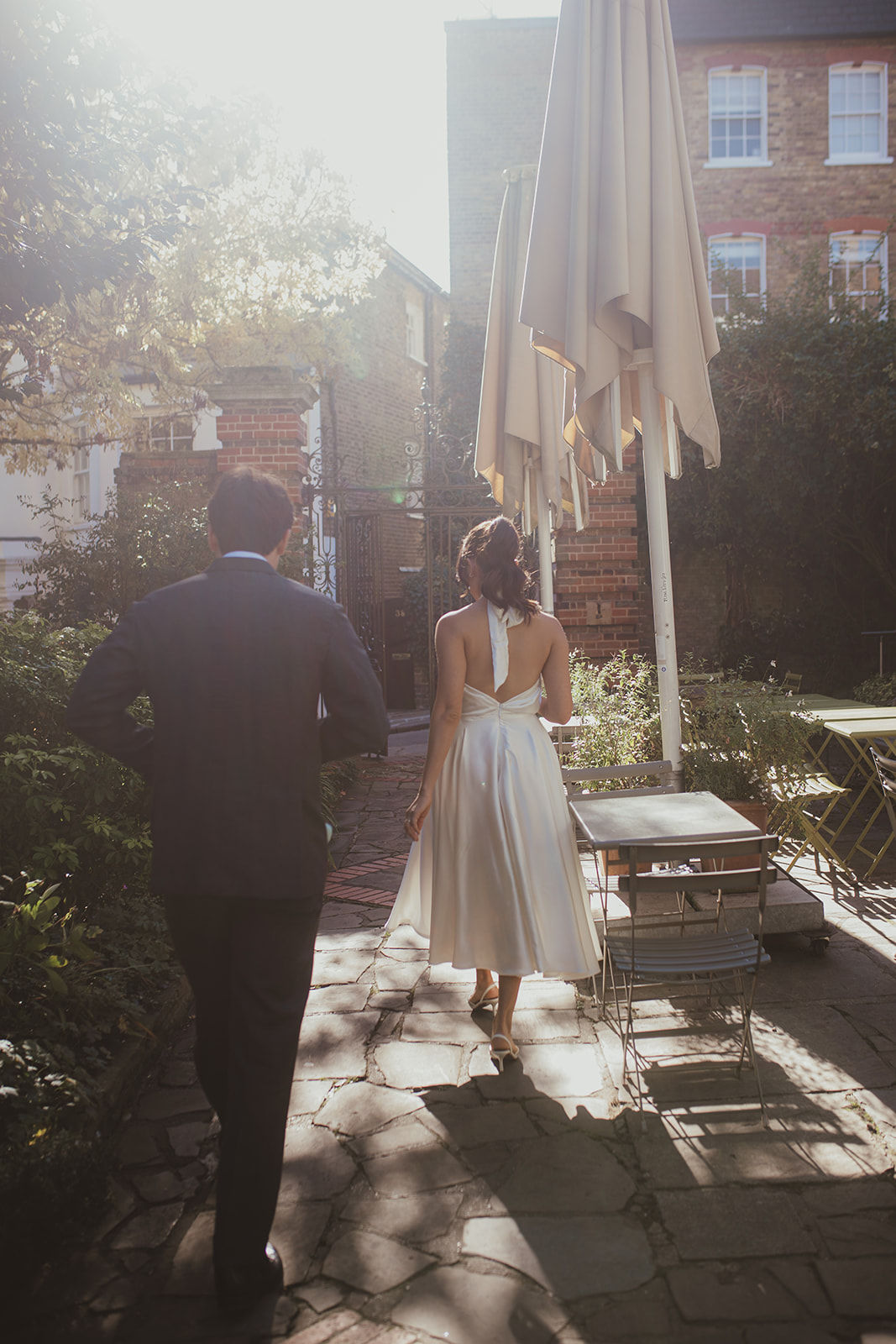 The back of bride and groom as they walk away from Burgh House in the soft sunlight
