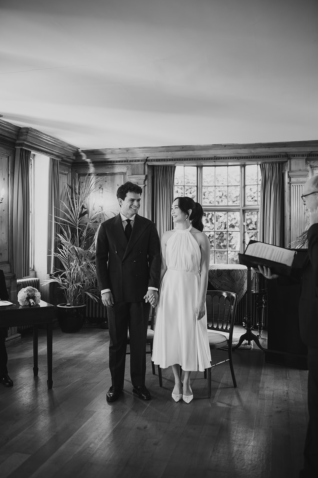 Bride and groom standing next to each other and laughing  during their wedding ceremony in Hampstead Heath